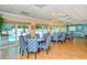 Bright community dining room with round tables and comfortable blue-patterned chairs adjacent to an outdoor pool area at 1350 N Portofino Dr # 402, Sarasota, FL 34242