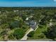 Aerial view showcasing the house and surrounding lush greenery, including a pond, and a long driveway at 13514 4Th E Plz, Bradenton, FL 34212