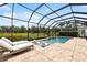 Inviting screened-in pool with sun loungers overlooking a serene backyard with lush greenery and a clear blue sky at 13606 Deep Blue Pl, Bradenton, FL 34211