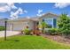 Well-manicured front yard featuring colorful landscaping, a lush green lawn, and a charming home exterior at 16606 Barnwood Pl, Lakewood Ranch, FL 34211