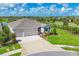 Beautifully landscaped front exterior of a home with a three-car garage, lush lawn, and colorful flowers at 16606 Barnwood Pl, Lakewood Ranch, FL 34211