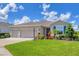 A home's inviting front exterior boasts a three-car garage and colorful landscaping at 16606 Barnwood Pl, Lakewood Ranch, FL 34211