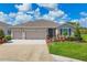 Charming home featuring a three-car garage and a well-maintained lawn with colorful landscaping at 16606 Barnwood Pl, Lakewood Ranch, FL 34211