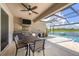 Covered outdoor kitchen and dining area with stainless steel grill, overlooking a sparkling pool and water view at 16606 Barnwood Pl, Lakewood Ranch, FL 34211