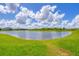 Scenic view of a serene pond surrounded by lush green grass on a sunny day at 16606 Barnwood Pl, Lakewood Ranch, FL 34211