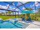 Inviting screened-in pool and spa area with lush green landscaping and a blue umbrella at 16606 Barnwood Pl, Lakewood Ranch, FL 34211
