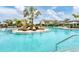 Stunning community pool surrounded by palm trees and beach chairs with clear blue water and pool stairs on a sunny day at 16606 Barnwood Pl, Lakewood Ranch, FL 34211