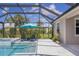 Screened-in pool area with lounge chairs and a blue umbrella; lush landscaping around the perimeter at 16606 Barnwood Pl, Lakewood Ranch, FL 34211