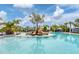 Stunning community pool surrounded by palm trees, beach chairs and cabanas with clear blue water on a sunny day at 16606 Barnwood Pl, Lakewood Ranch, FL 34211