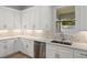 A modern kitchen provides white cabinets, stainless appliances, and a window overlooking the backyard at 17113 Malta Ave, Port Charlotte, FL 33954