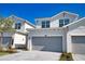 Close-up of garages of modern townhomes, featuring gray doors, immaculate landscaping, and bright blue skies at 17715 Boracay Ct # 202, Venice, FL 34293