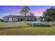 Home with a circular driveway, white fence, and green grass with the sky turning from dusk to night at 2005 21St W St, Palmetto, FL 34221
