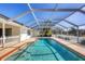 A covered pool with clear blue water is surrounded by a red brick border and white beams under a clear blue sky at 2005 21St W St, Palmetto, FL 34221