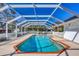 A covered pool with clear blue water is surrounded by a red brick border and white beams under a clear blue sky at 2005 21St W St, Palmetto, FL 34221