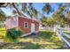 A red shed with a white door and trim sits on a grassy lawn with a white fence and green trees at 2005 21St W St, Palmetto, FL 34221
