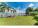 Backyard featuring lush green lawn, black fence, and stunning views of the lake at 204 Maraviya Blvd, Nokomis, FL 34275