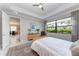 Stylish bedroom featuring a tray ceiling, ceiling fan, and a tranquil view of the lush greenery outside at 204 Maraviya Blvd, Nokomis, FL 34275