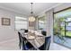 Dining room features a stone table, black leather chairs, and sliding doors to the lanai and water view at 204 Maraviya Blvd, Nokomis, FL 34275