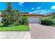 Charming single-story home featuring a brick driveway, well-manicured lawn, and lush tropical landscaping at 204 Maraviya Blvd, Nokomis, FL 34275