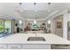 Open kitchen with stainless steel sink overlooks the living room with tray ceiling and decorative shelving at 204 Maraviya Blvd, Nokomis, FL 34275