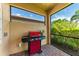 Outdoor kitchen on the screened lanai with a red grill and views of the green landscaping at 204 Maraviya Blvd, Nokomis, FL 34275