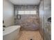 Luxurious bathroom featuring a soaking tub and stunning walk-in shower with decorative stone-look tile and pebble floor at 2213 Avenue C, Bradenton Beach, FL 34217