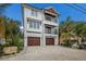 Coastal three-story home featuring double balconies, a two-car garage, and tropical landscaping at 2213 Avenue C, Bradenton Beach, FL 34217