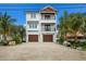 Coastal three-story home featuring double balconies, a two-car garage, and tropical landscaping at 2213 Avenue C, Bradenton Beach, FL 34217
