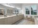 Bright bathroom featuring dual sinks, ample storage, soaking tub, and large window at 22343 Panther Loop, Bradenton, FL 34202