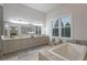Bright bathroom featuring a double sink vanity, a large soaking tub, and natural light from a window at 22343 Panther Loop, Bradenton, FL 34202