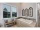 A soaking tub with a bench seat and garden view is an oasis of tranquility in this bathroom at 22343 Panther Loop, Bradenton, FL 34202