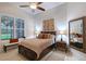 Bedroom showcasing a large window, ceiling fan, bed, area rug, decorative mirror, and floral artwork at 22343 Panther Loop, Bradenton, FL 34202