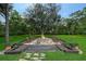 Backyard fire pit surrounded by mature trees, landscaping and chairs at 22343 Panther Loop, Bradenton, FL 34202