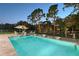 Backyard pool with lounge chairs, an umbrella, and mature landscaping at 22343 Panther Loop, Bradenton, FL 34202