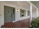 Inviting front porch featuring brick flooring, white columns, and a beautifully painted front door at 2430 Catalonia S Way, St Petersburg, FL 33712