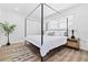 Serene bedroom with a four-poster bed, white linens, wood floors, and natural light from the window at 3016 Gulf Dr, Holmes Beach, FL 34217