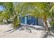 Charming exterior with a blue facade, gravel yard, palm trees and comfortable seating area at 3016 Gulf Dr, Holmes Beach, FL 34217