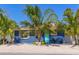 Charming home with a blue exterior, turquoise door, palm trees, and sandy yard at 3016 Gulf Dr, Holmes Beach, FL 34217