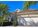 Charming single-story home featuring a red tile roof, arched windows and a two-car garage framed by lush green tropical landscaping at 303 9Th E Ave, Palmetto, FL 34221