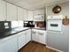 Bright kitchen with white appliances, cabinets, and sink; enhanced by wood-look flooring and sleek countertops for a modern feel at 3402 Shingle Oak Ter, Sarasota, FL 34237