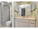Charming bathroom featuring a vanity and shower with glass door, complemented by decorative wallpaper at 3500 El Conquistador Pkwy # 128, Bradenton, FL 34210