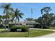 Community clubhouse with American flag, surrounded by lush landscaping and mature palm trees at 3752 Collins St # 508, Sarasota, FL 34232