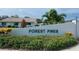 The 'Forest Pines' community sign surrounded by lush greenery and colorful tropical foliage at 3752 Collins St # 508, Sarasota, FL 34232
