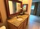 Well-lit bathroom featuring a granite countertop vanity, large mirror, and modern fixtures at 390 301 W Blvd # 2C, Bradenton, FL 34205