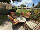 An inviting patio setting with bright, cushioned chairs and a round table, nestled within a well-manicured lawn and landscaping at 390 301 W Blvd # 2C, Bradenton, FL 34205