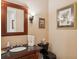 Elegant half-bath featuring a wood vanity, black toilet, and framed artwork at 4224 Boca Pointe Dr, Sarasota, FL 34238