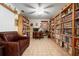 Study filled with bookshelves, desk, computer, chair, leather couch, and a ceiling fan at 4513 Hidden River Rd, Sarasota, FL 34240