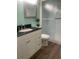 Bathroom featuring vanity with black countertop and framed mirror, toilet and enclosed shower at 4520 47Th W Ave # 103, Bradenton, FL 34210