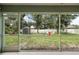 View of a grassy fenced backyard, firepit, shed and wooded area seen from the lanai at 4565 Eldron Ave, North Port, FL 34286