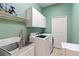 Well-lit laundry room with a sink, modern washer and dryer, and storage cabinets at 4958 Gardiners Bay Cir, Sarasota, FL 34238